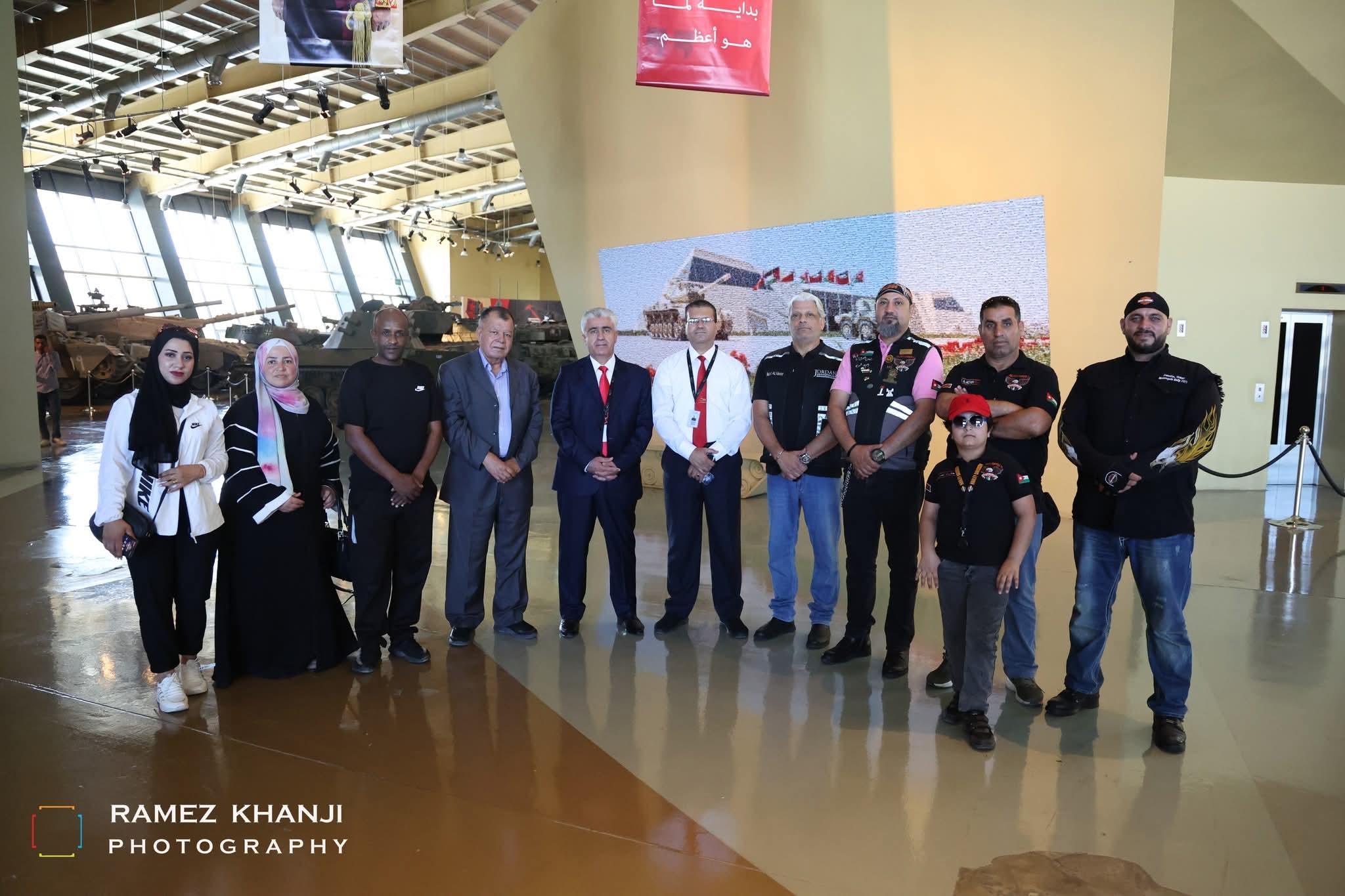 زيارة جماعية لقاعة متحف تُعرض فيها مدرّعات عسكرية، وأعضاء من النادي مع مسؤولي المكان